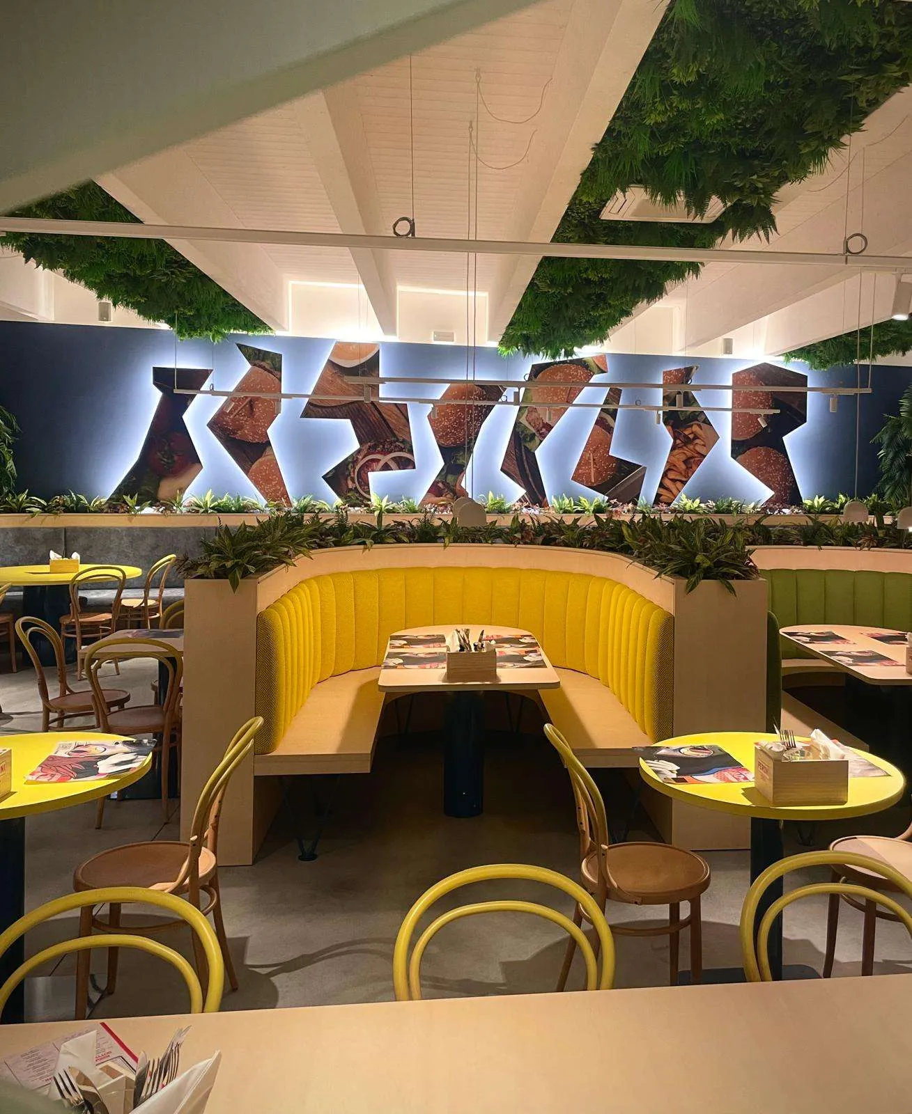 Installazione murale con un hamburger rappresentato in più segmenti geometrici separati e retroilluminati